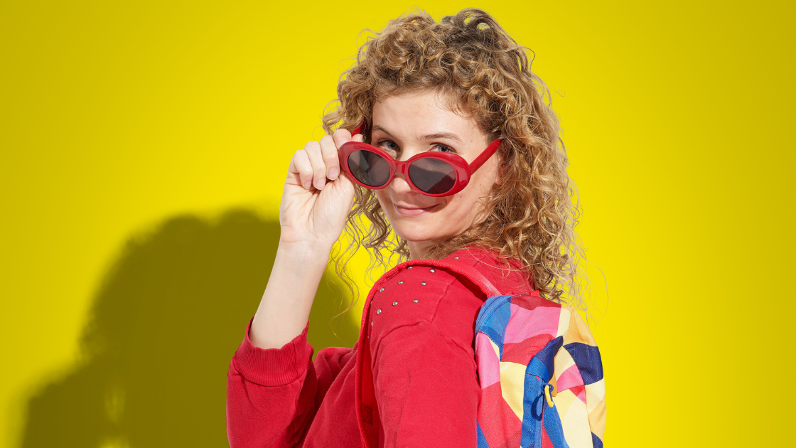 donna sorridente con occhiali da sole e zainetto
