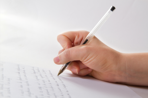 Persona ha in mano una penna e scrive su un foglio